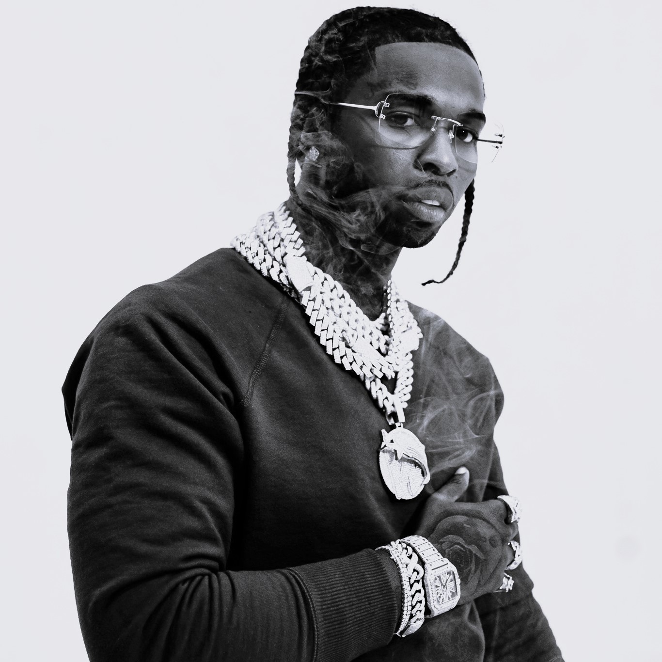 Portrait of Pop Smoke with one hand on his chest, showing jewelry on his hand and around his neck.